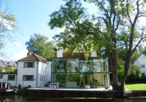 Een stenen dorpshuis met een glazen bijgebouw